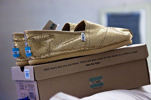 Photo of a pair of TOMS shoes sitting on top of the branded shoe box